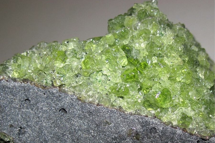 Green Peridot on a grey stone found at the Peridot Mesa Mine