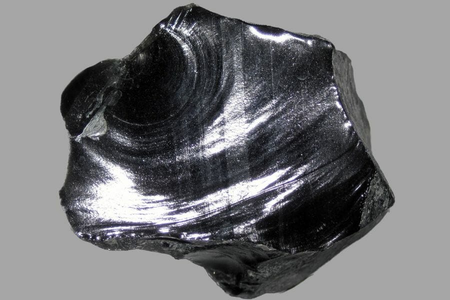 A shimmering black Obsidian against a light gray background