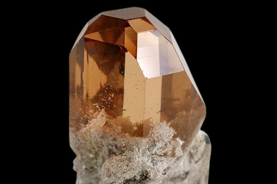 A shiny, polished, Brown Topaz atop a crystal