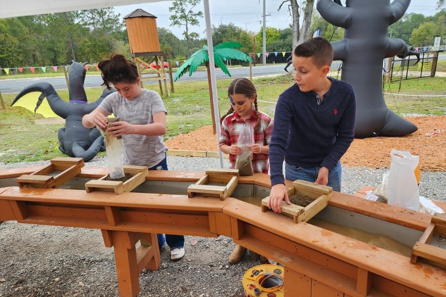 Three kids about to start gem mining as they pour mining rough on the sifter of Bradford Bamboo's mining sluice