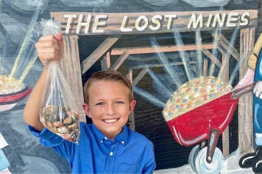 A kid happily raises a plastic bag containing the gems and special rocks he found at the Lost Mines of Atlantis