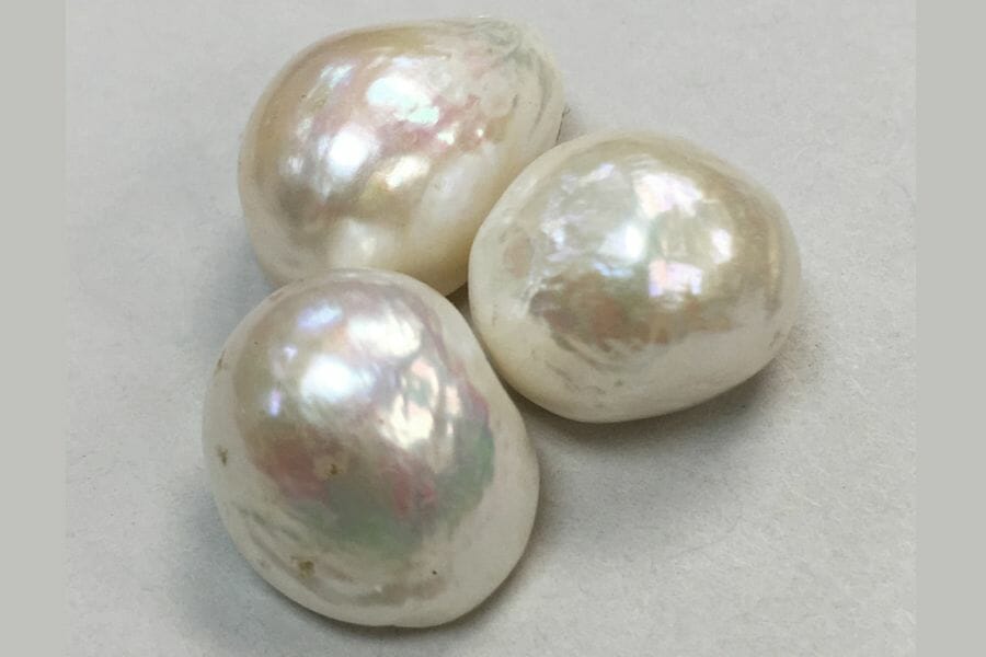Three beautiful pearls laying together on a grayish white surface