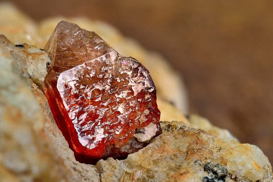A reddish orange Zircon attached to a rock that was found while gem mining