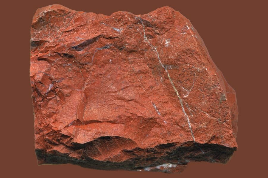 A huge piece of red Jasper against a brown background