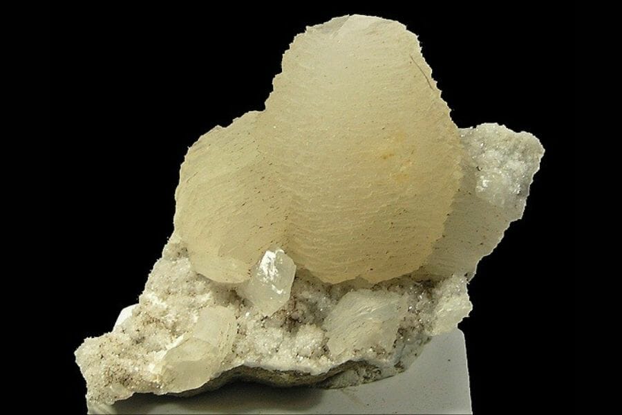 A delicate-looking translucent Calcite attached atop a stone.