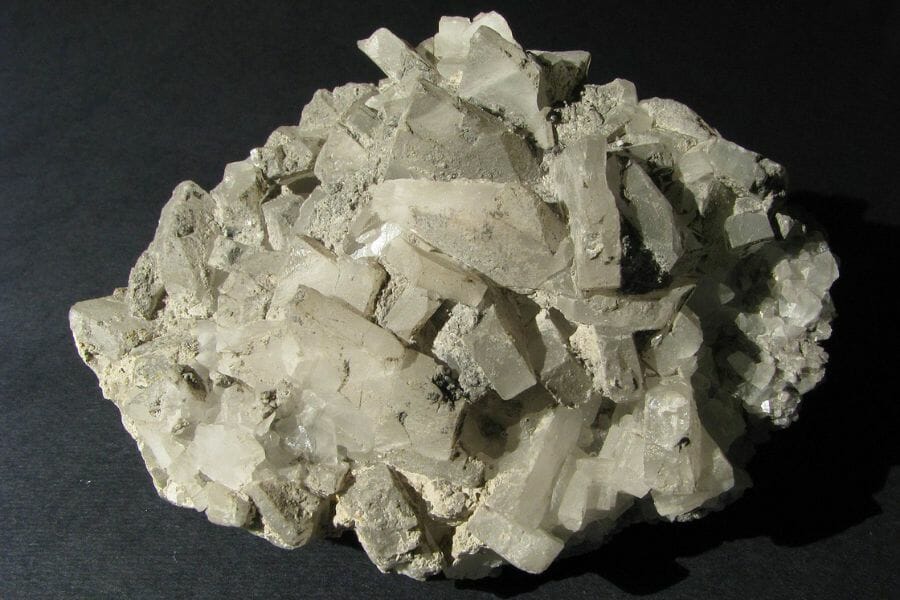 An intricate white Barite laying on a black surface