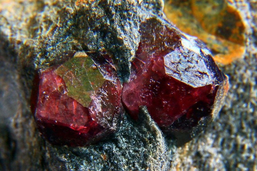 Two pieces of deep red Garnets protruding from a piece of rock