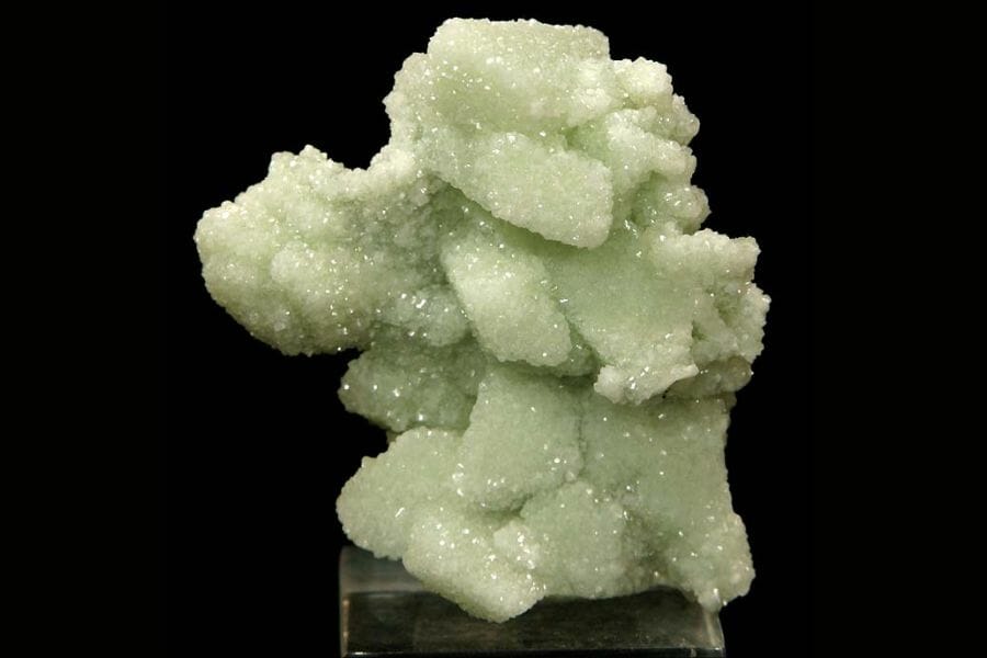 A shiny, almost glowing light green Prehnite against a black background