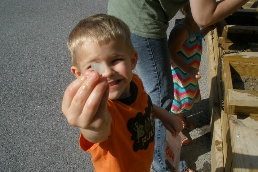 A kid in orange shirt proudly shows the gemstone that he found at the Penn's Cave & Wildlife Park