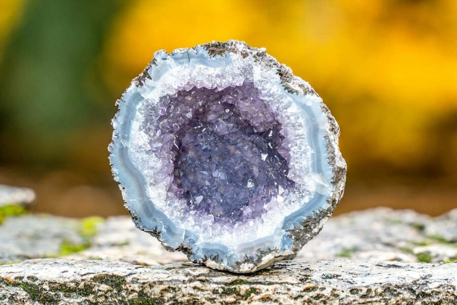 A blue and purple geode sitting on a rough surface