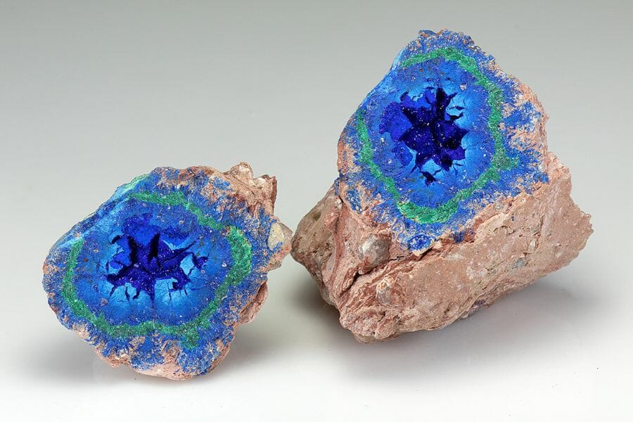 A vibrant blue azurite geode lined with green minerals cracked open w