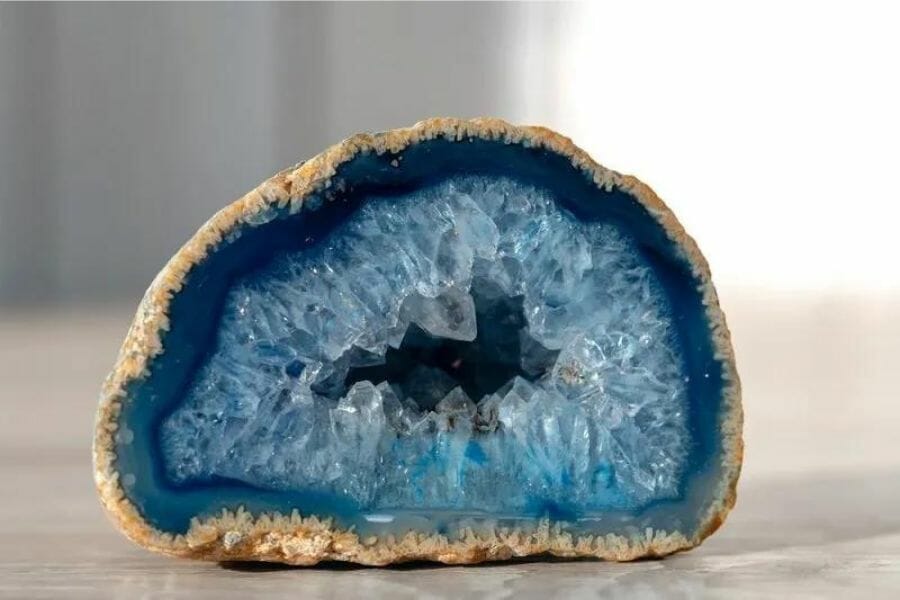 A vibrant blue agate geode sitting on a smooth surface