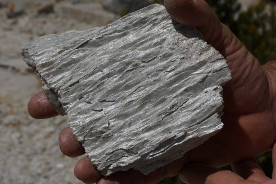 A beautiful, wave-like textured gray Phyllite held by a hand