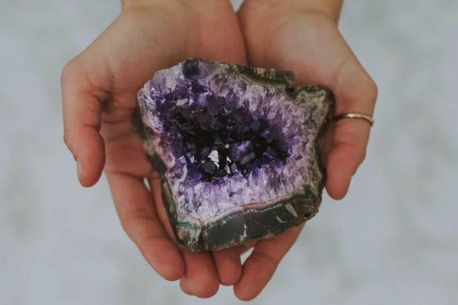 An amethyst geode held on palms