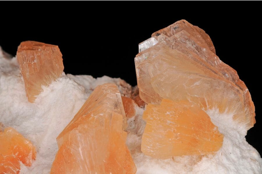 A bunch of light orange-colored Heulandite attached to a white rock