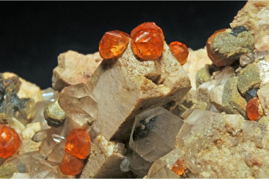 Round pieces of bright orange Spessartite Garnet attached to rocks
