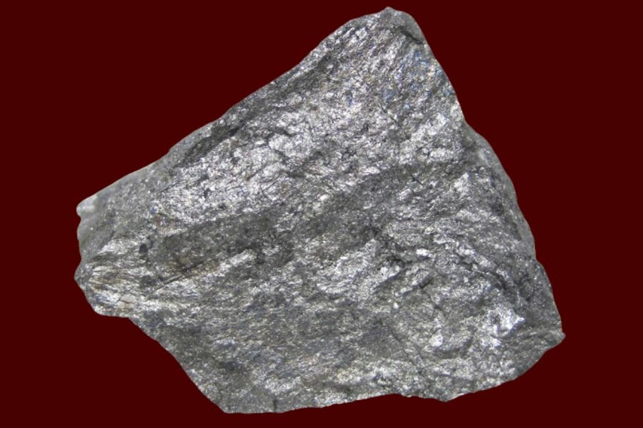 A large sample of silver Cobaltite on a maroon background