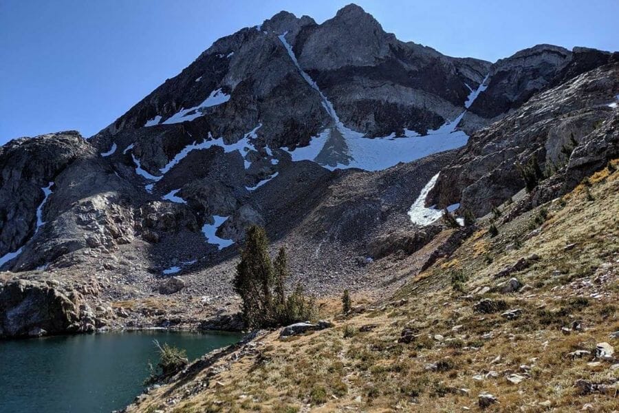 Slate mountain with snow in some parts and a lake at its foot 