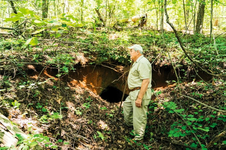 A man standing in front of an excavation hole at Hog Mountain