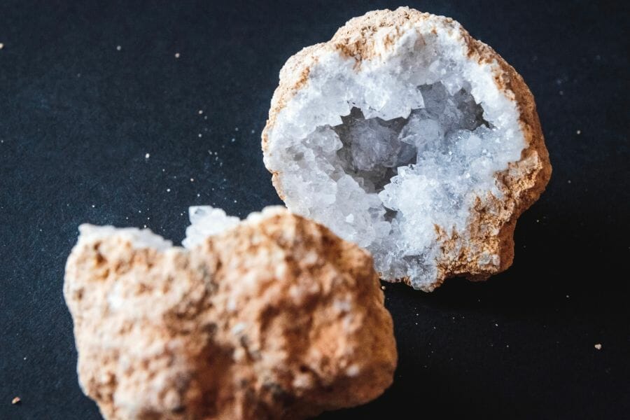 Two sides of a cracked open geode with white crystals