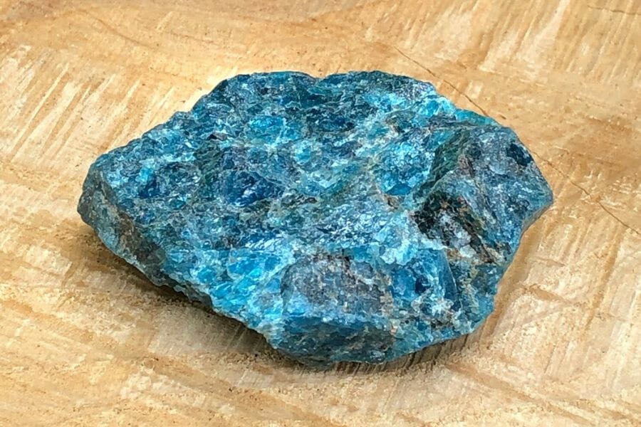 A stunning blue apatite laying on a brown wooden surface