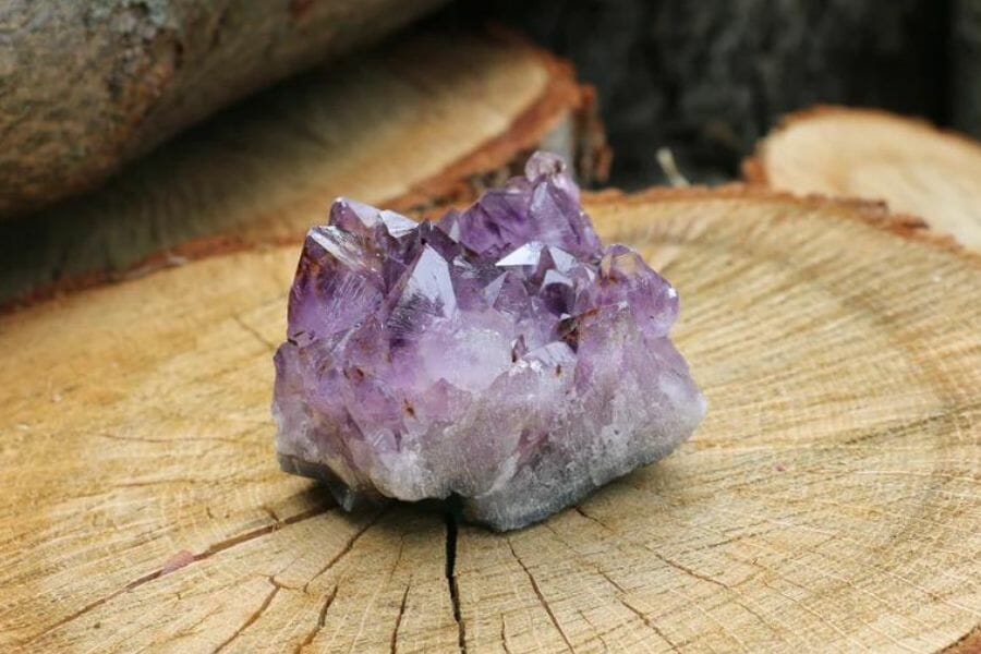A gorgeous amethyst crystal on a wooden log