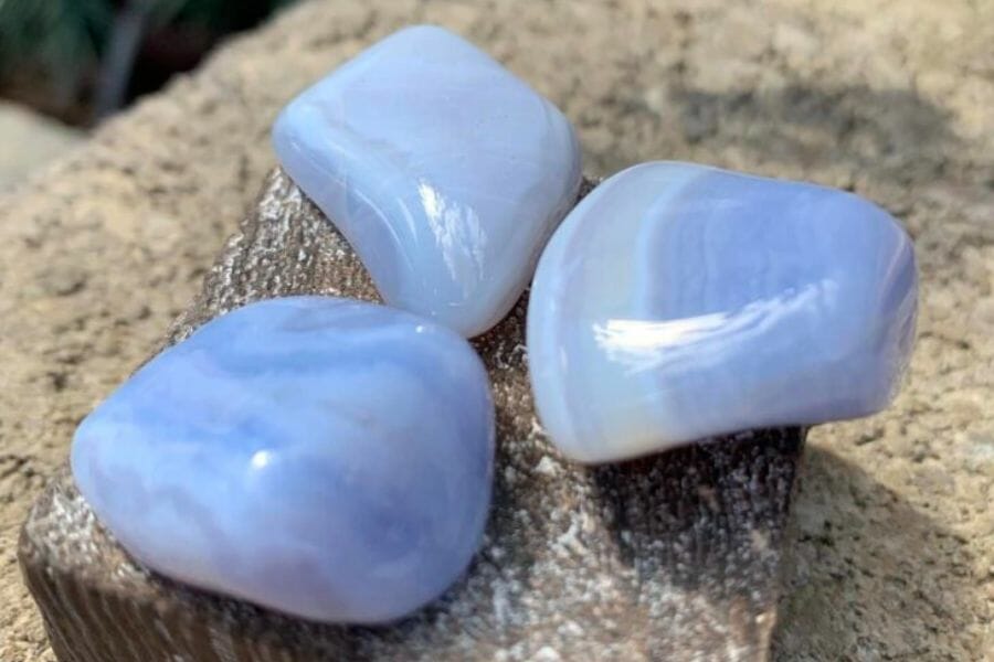 Three samples of stunning light blue Chalcedony crystals on a rough ground