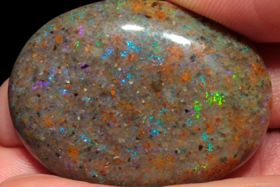 A round piece of Louisiana Opal exhibiting rainbow-colored specks on a grayish crystal