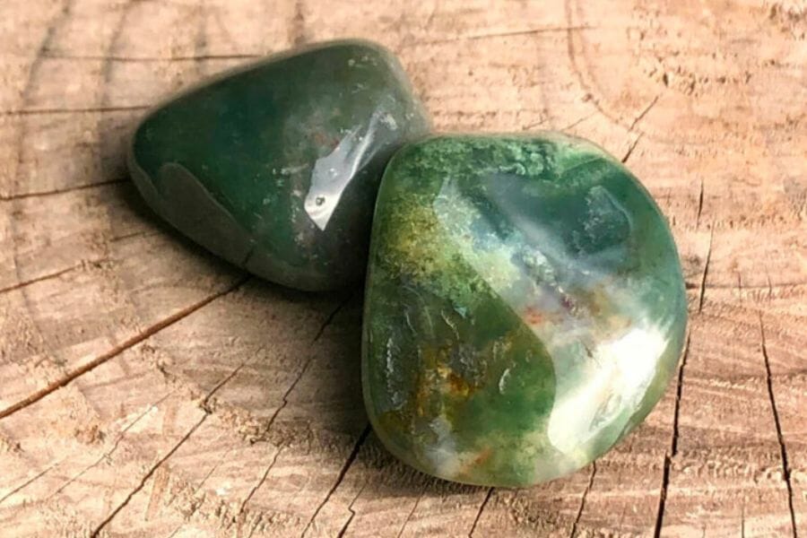 Two beautiful Moss Agate crystals on a wooden surface