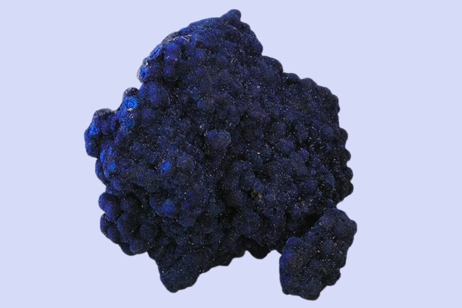 An intricate sample of a blue Azurite against a pastel purple background