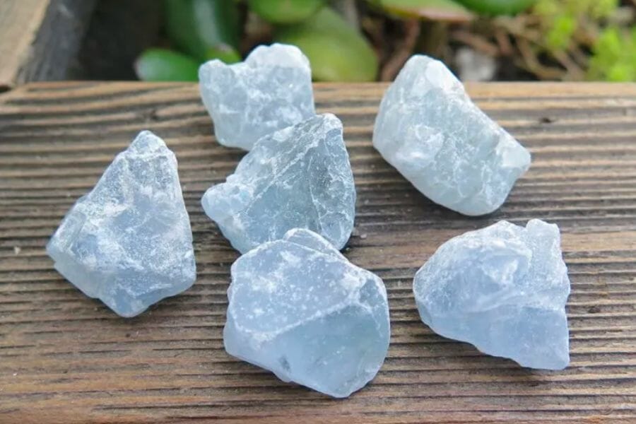 Six pieces of differently-shaped grayish blue Celestite crystals on a wooden surface