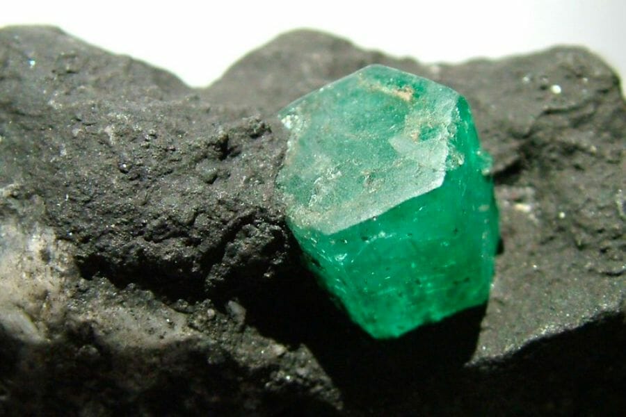 A piece of green Emerald crystal attached to a rock