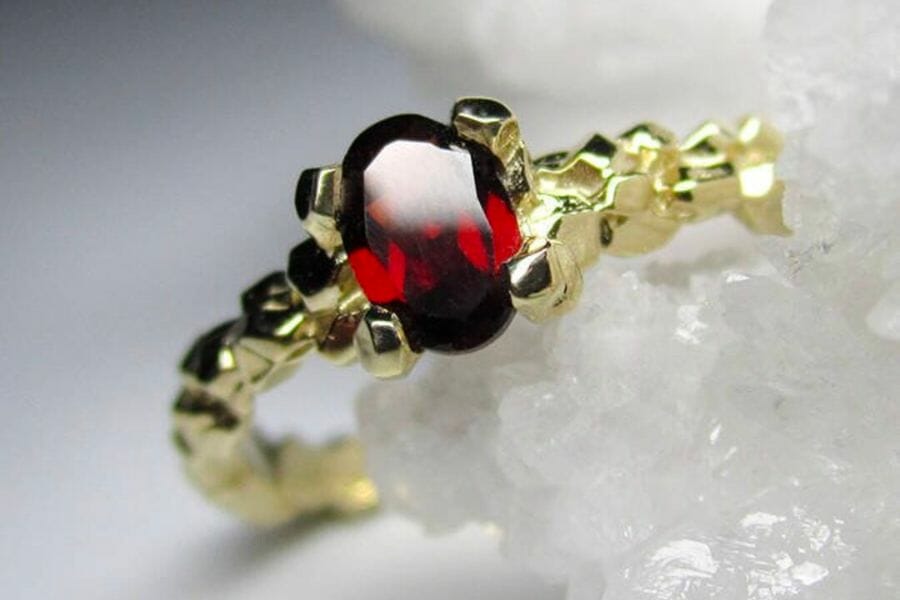 A gold ring adorned with an oval-shaped deep red Almandine Garnet