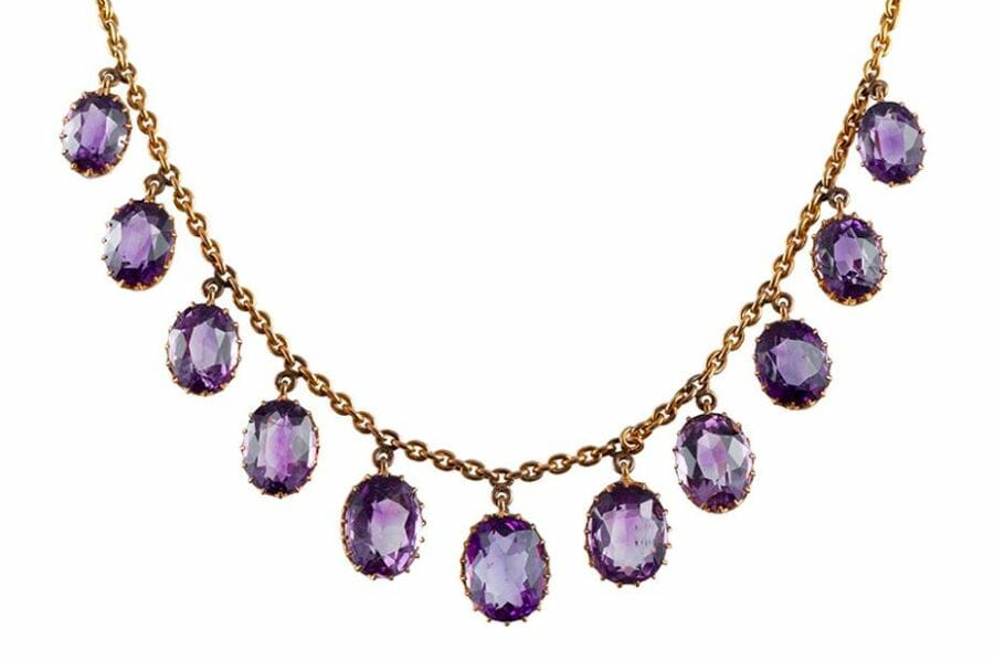 A stunning golden necklace adorned by round pieces of faceted Amethysts
