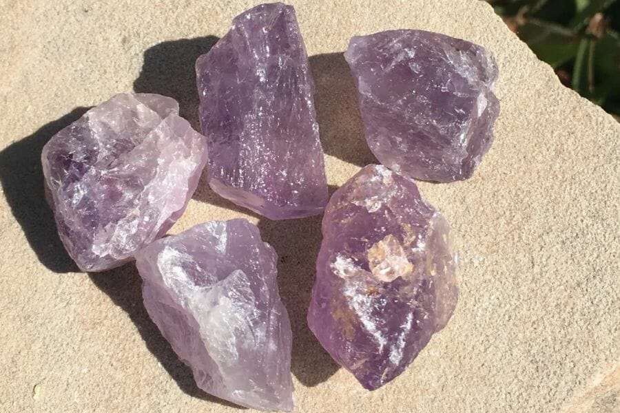 Five glowing amethyst laying on a white smooth surface