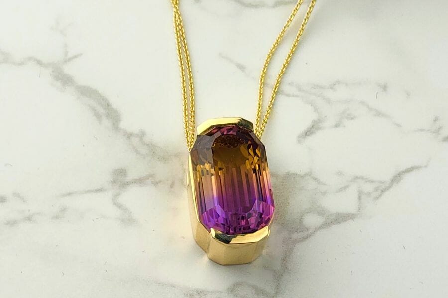 A stunning piece of polished Ametrine set as a pendant of a gold necklace