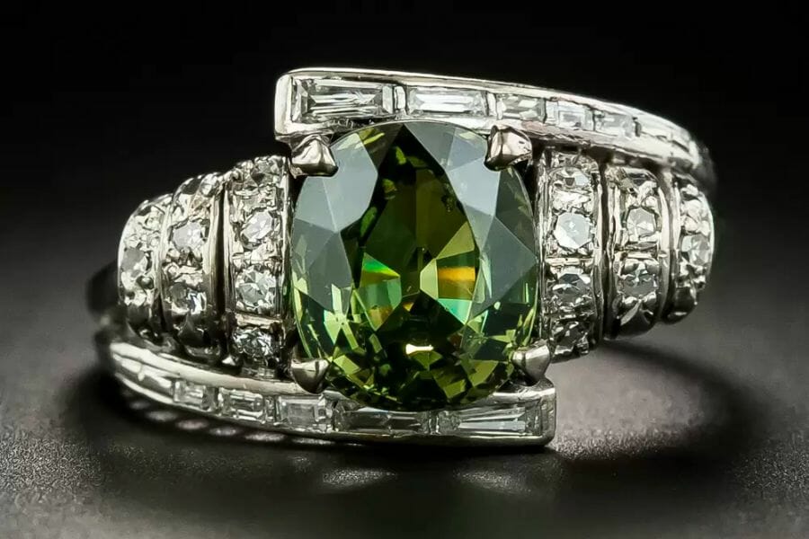 A breathtaking close up photo of a sparkling green Andradite Garnet centering a white gold ring 