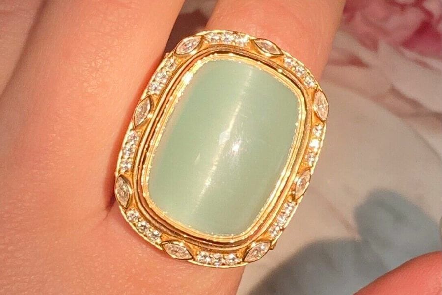A close up look at a Cat's Eye Aquamarine on a gold ring with details of small white diamonds