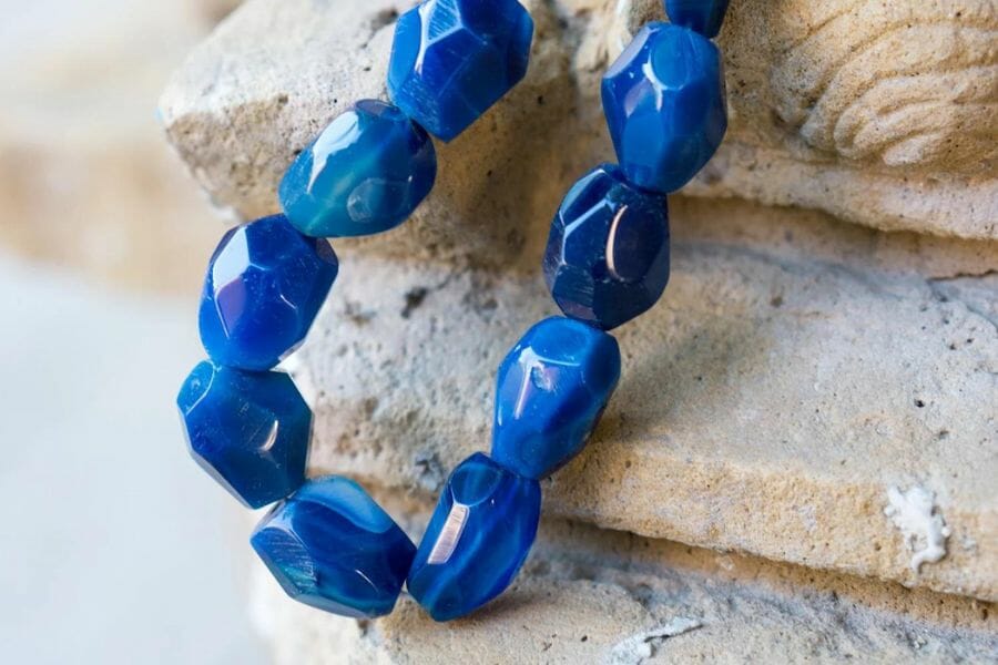 A mesmerizing blue onyx necklace placed on a rough rock-like surface