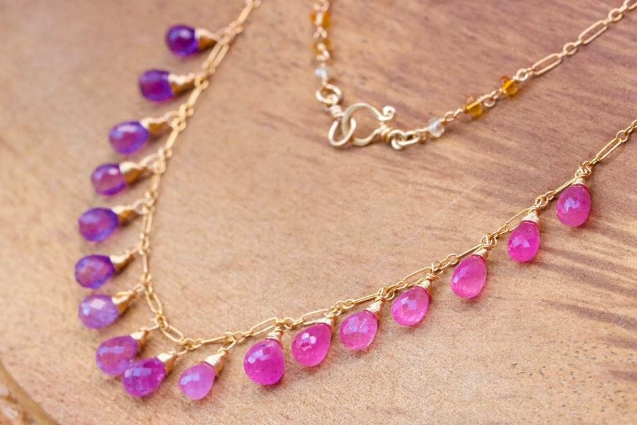 A golden necklace with teardrop Color Change Sapphires that change color from pink to purple, depending on the angle