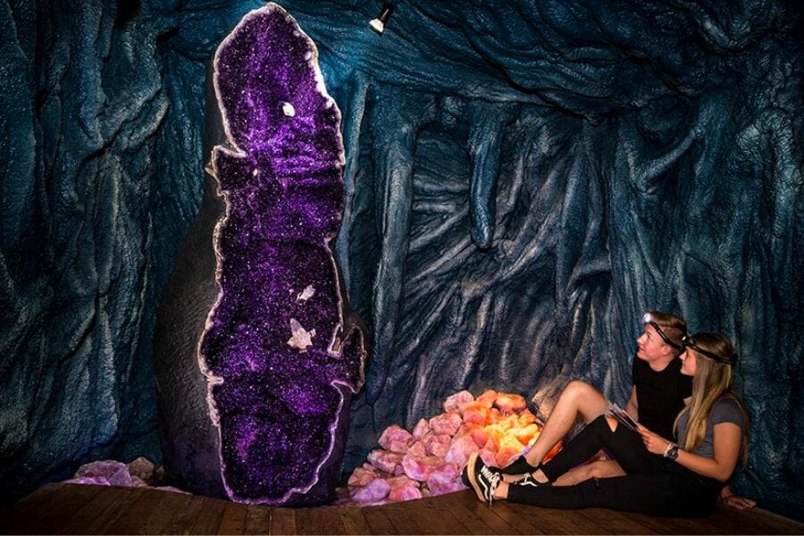 Over 10-feet tall Amethyst geode called the Empress of Uruguay being observed by a couple
