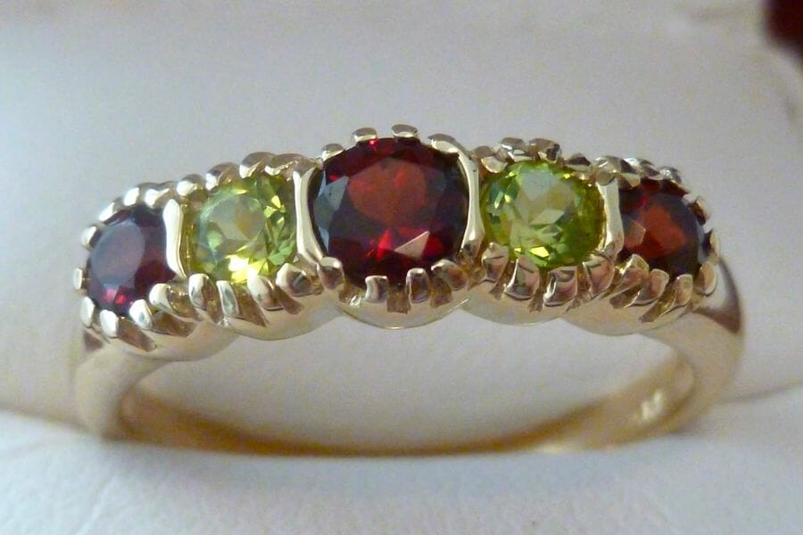 A piece of ring with several pieces of deep red and light green Garnets