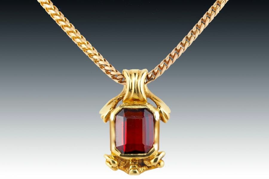 A close look at the reddish orange Hessonite Garnet set on a gold pendant and necklace