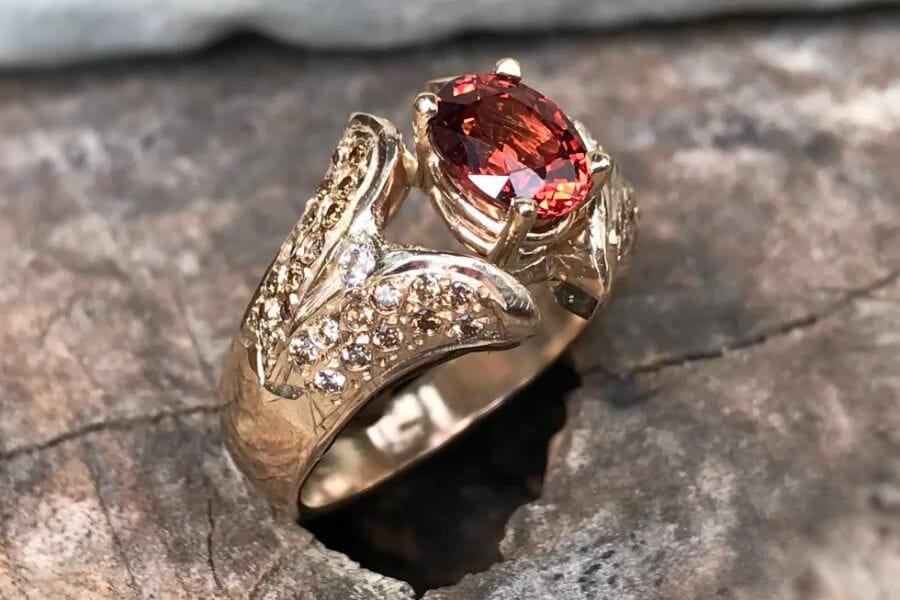 A beautiful pinkish-red Malaia stone set as center stone on an intricate gold ring
