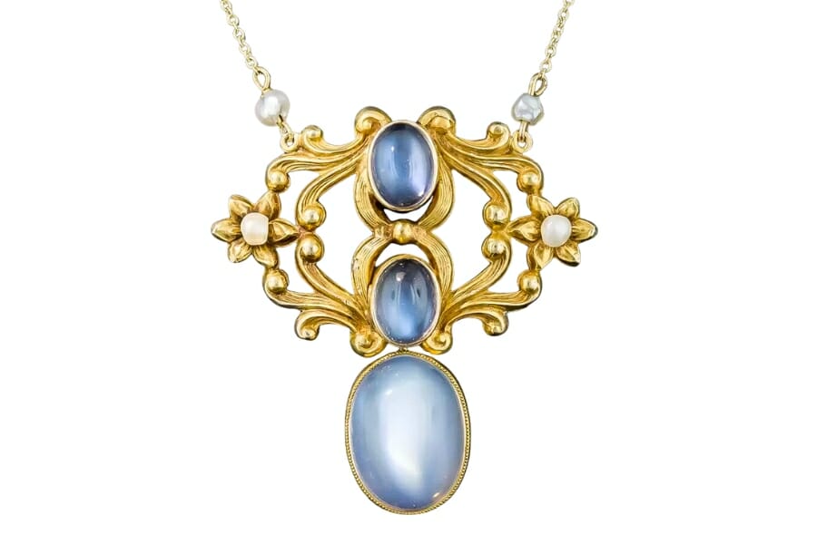 An intricately-designed gold pendant adorned with bluish white Moonstone cabochons