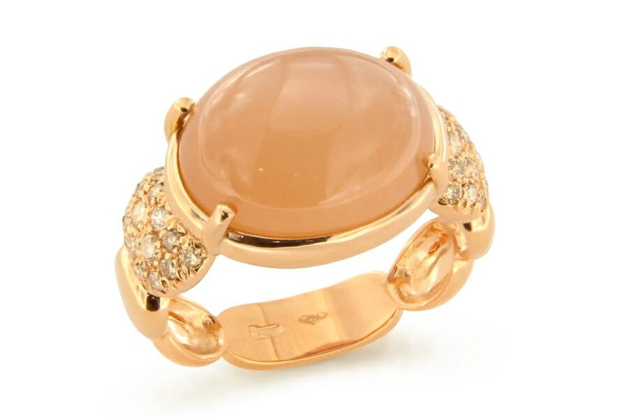A stunning peachy pink Moonstone cabochon set as a center stone on a gold ring