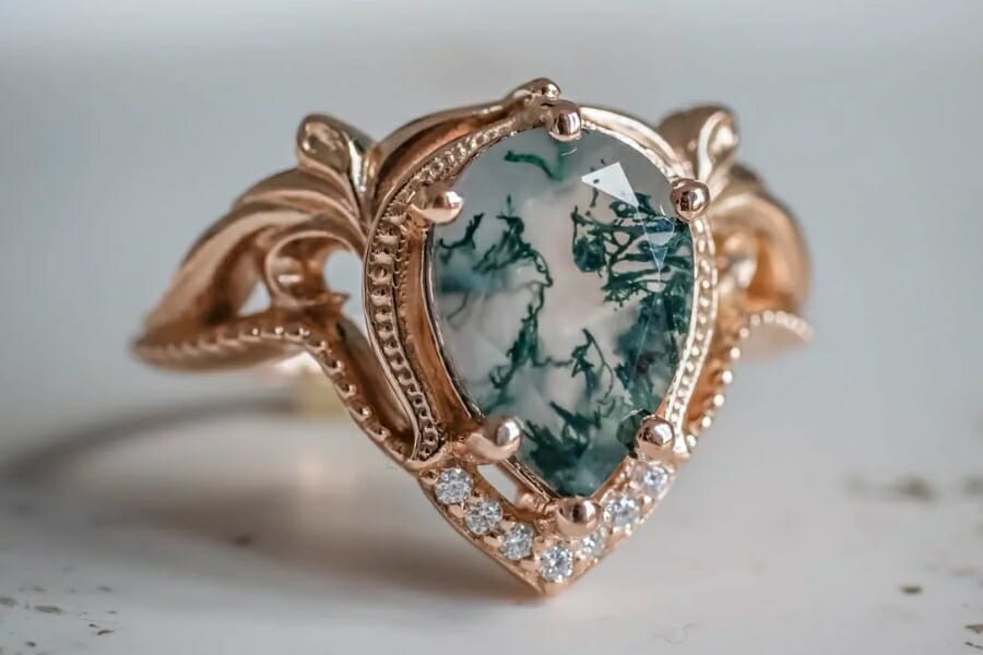 A gold ring adorned by a teardrop-shaped Moss Agate
