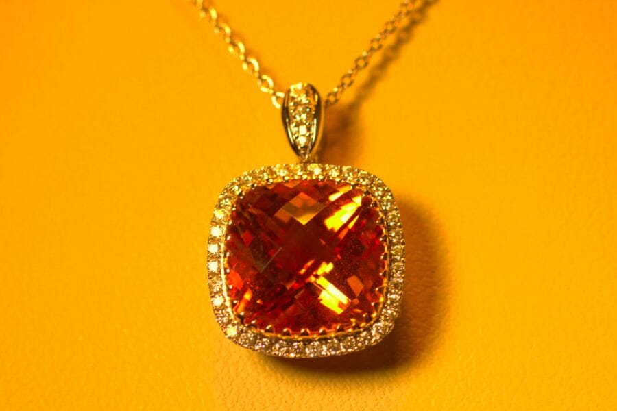 A breathtaking close up photo of a faceted Orange Citrine adorining a golden pendant and necklace