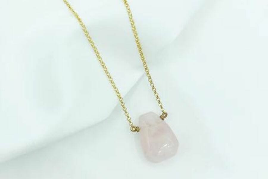 A pretty light pink quartz necklace with a gold chain
