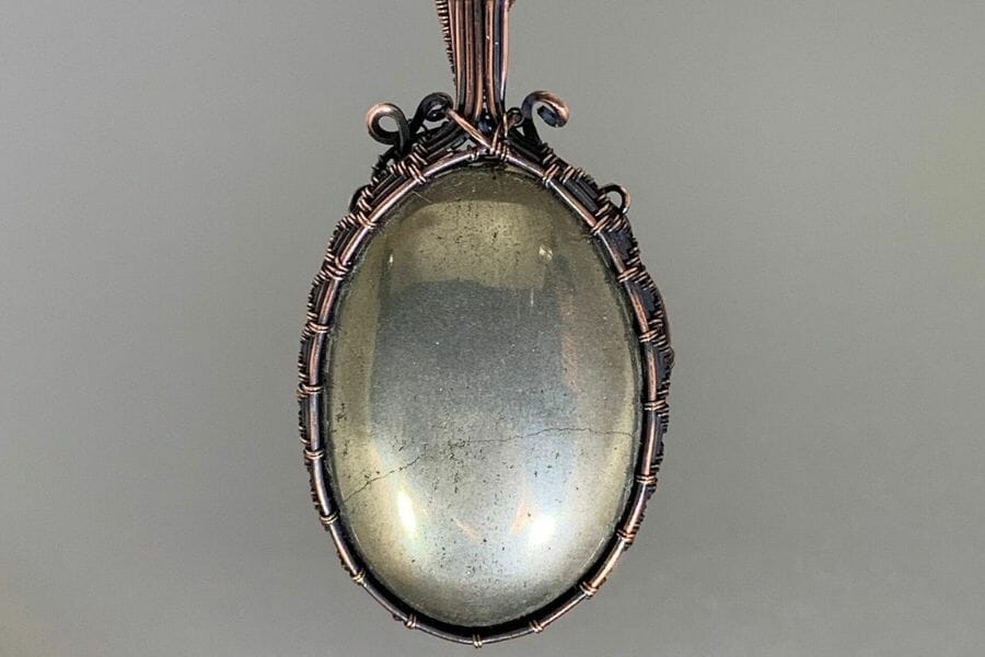 A shiny, almost reflective Pyrite Cabochon set on a bronze pendant
